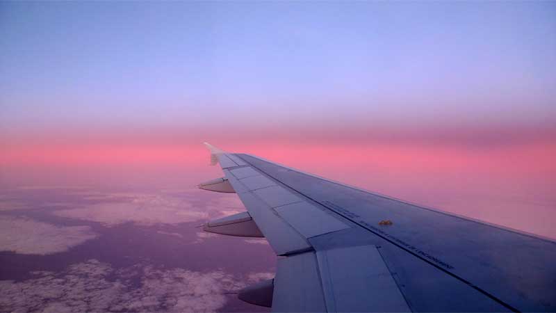 旅客機の窓から見える地平線と朝焼け