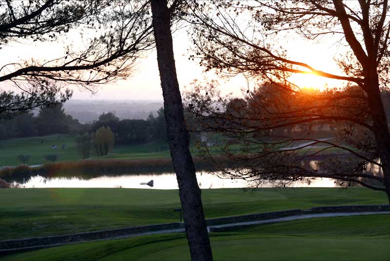 ゴルフ場に沈む夕日。池も見える。