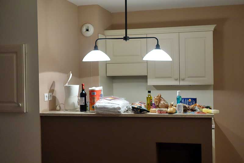 プロヴァンスのコンドミニアムのキッチンコーナー。対面カウンターの上におしゃれな照明がついている。
