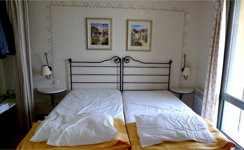 プロヴァンスのコンドミニアムの寝室。シングルベッドが二つ置かれている。